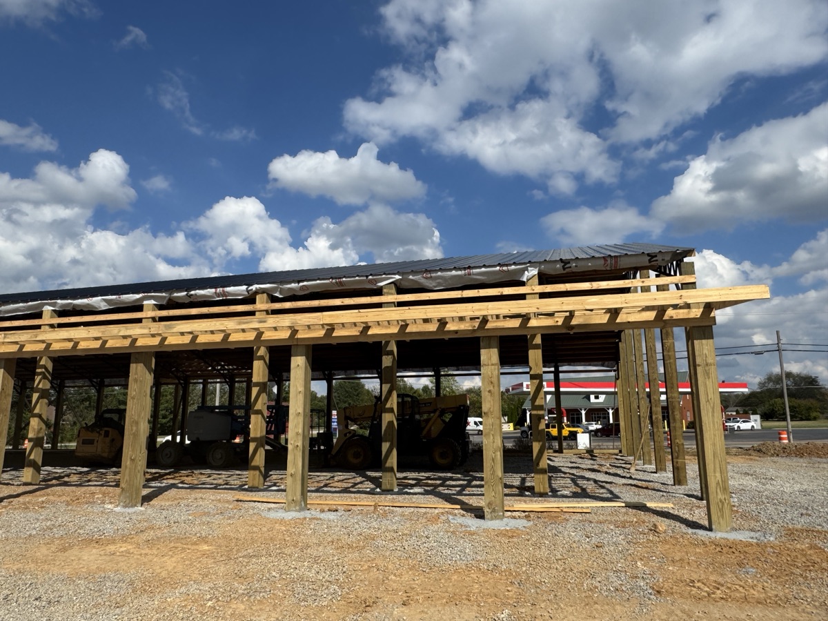 Exterior view of Thompsons Station Hardware construction in Franklin, TN, showcasing significant progress with both roof and entrance framing visible.